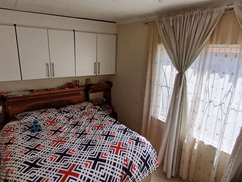 A bedroom featuring built-in cupboards and security bars on the windows, requiring cosmetic updates to improve the overall condition and appeal.
