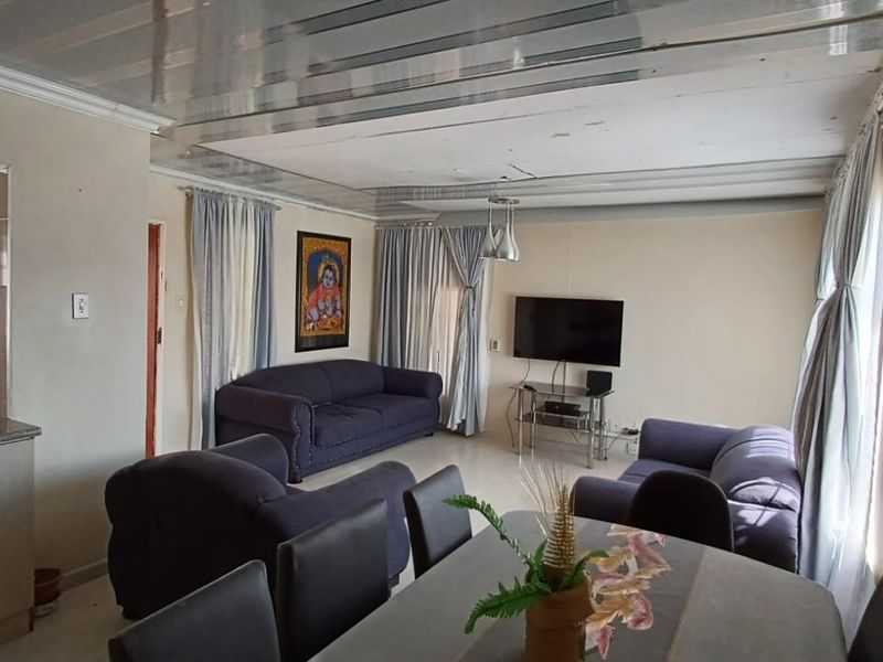 Open-plan living and kitchen area featuring tiled flooring, fitted cabinetry, and a suspended ceiling, offering a functional layout for daily living.