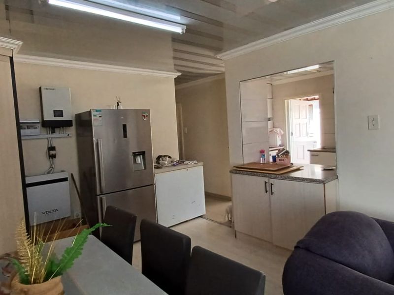 Open-plan living and kitchen area featuring built-in cabinetry, laminate flooring, and an integrated solar inverter system.