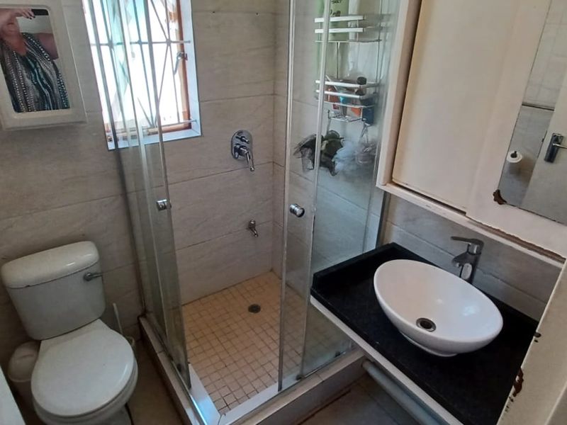 Compact bathroom featuring a glass shower enclosure, vessel sink on a vanity countertop, and tiled wall finishes.