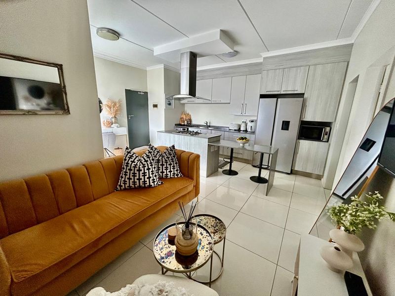 Modern open-plan living area featuring a contemporary kitchen with built-in cabinetry, stainless steel appliances, and sleek tiled flooring throughout.