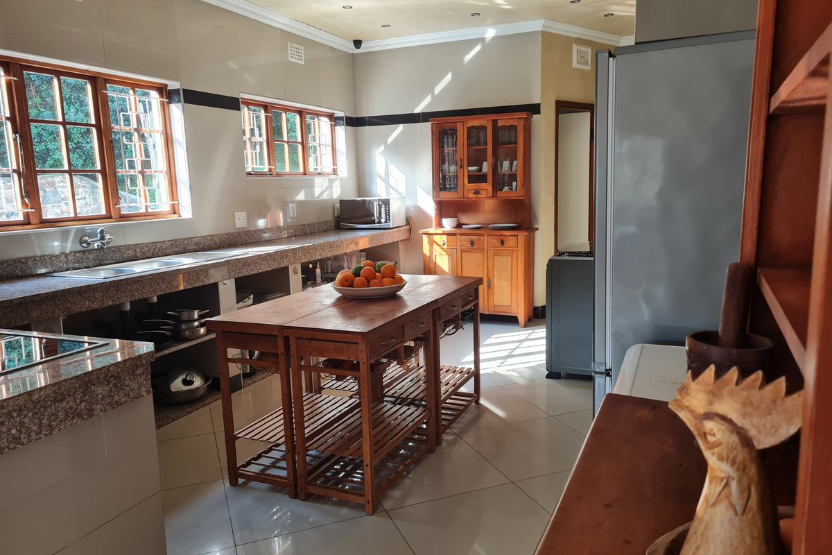 Spacious kitchen featuring granite countertops, double basin sink, tiled flooring, and ample natural light through wooden-framed windows.