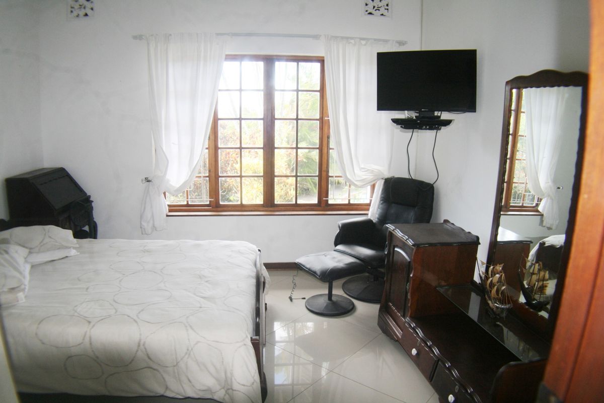 A bedroom featuring tiled flooring and a timber-framed window, providing a functional space with neutral wall finishes.