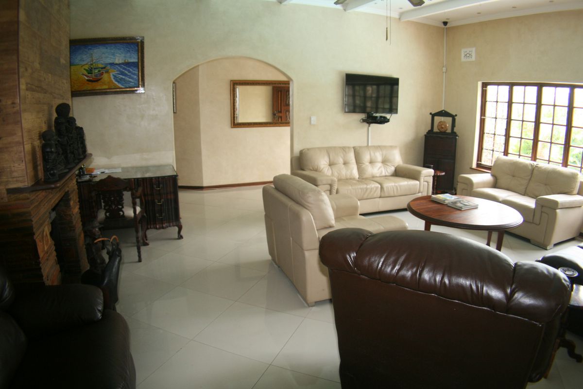 Spacious living room featuring a brick fireplace, tiled flooring, and an arched entryway, offering a comfortable and traditional layout.