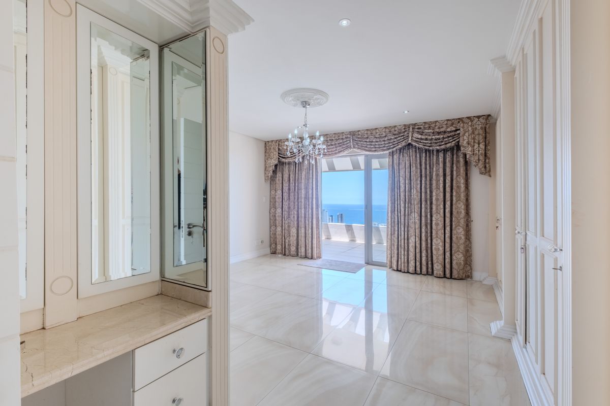 Spacious bedroom featuring polished porcelain flooring, built-in vanity with marble top, and direct access to a private balcony with ocean views.
