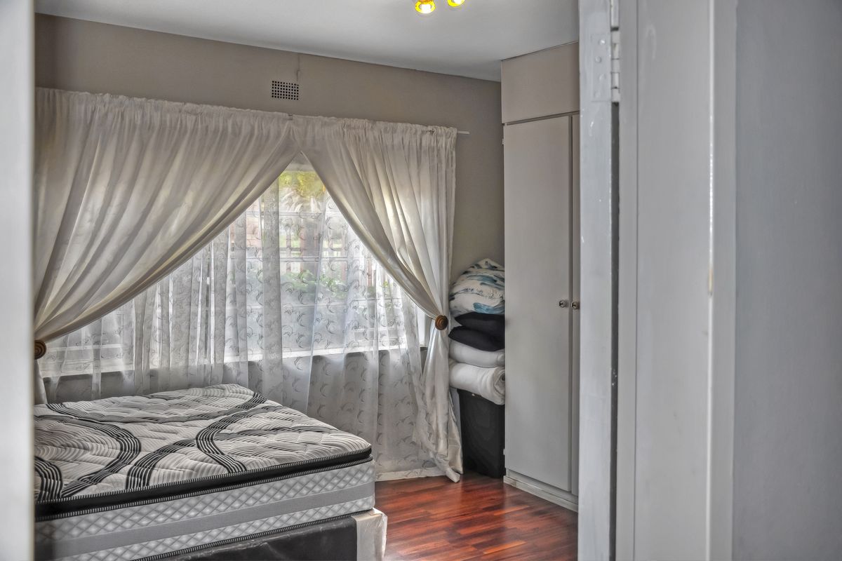 A bedroom featuring built-in cupboards and timber flooring, offering a functional space with natural light through the window.
