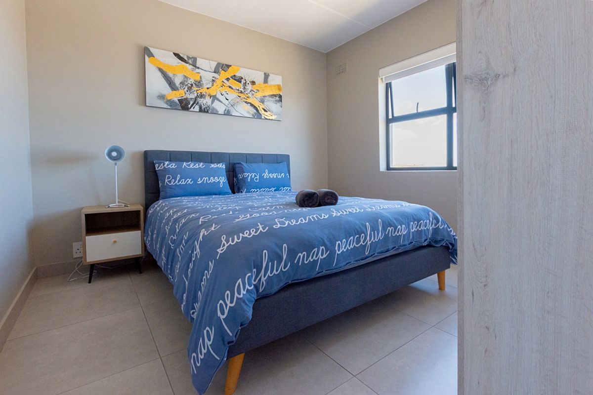 A well-maintained bedroom featuring neutral tiled flooring, a large window for natural light, and built-in cabinetry.