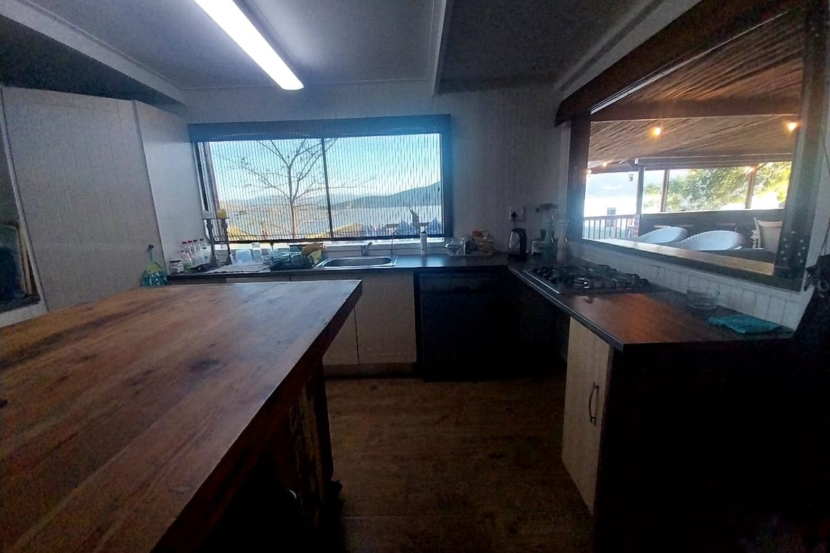A functional kitchen featuring a large wooden island, built-in hob, and sink with a view, offering a practical layout for meal preparation.