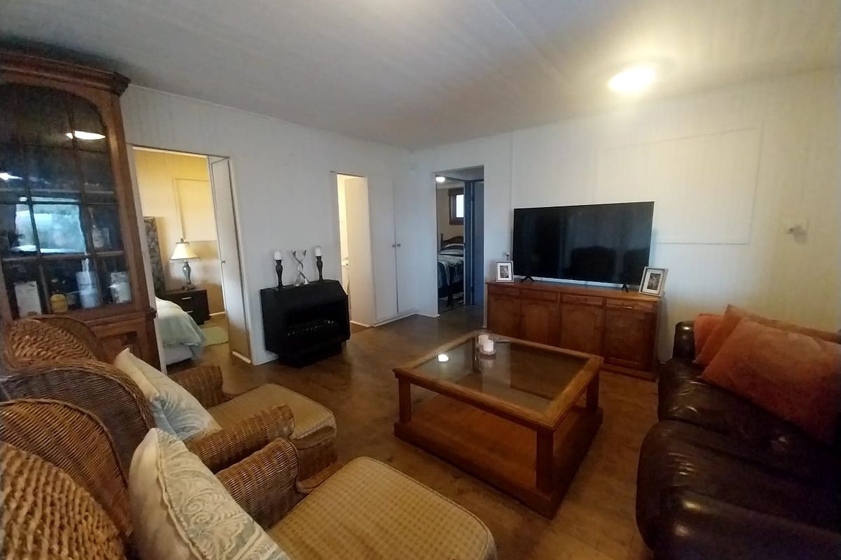 A living room featuring wood-look flooring and access to adjacent bedrooms, providing a functional and comfortable living space.