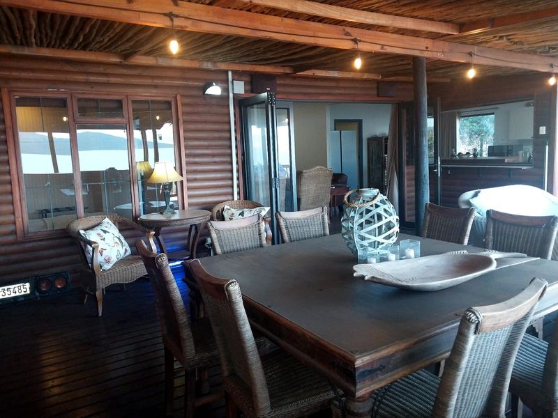 A covered outdoor patio area featuring timber log walls, a rustic thatched ceiling, and bi-fold doors leading into the main living space.