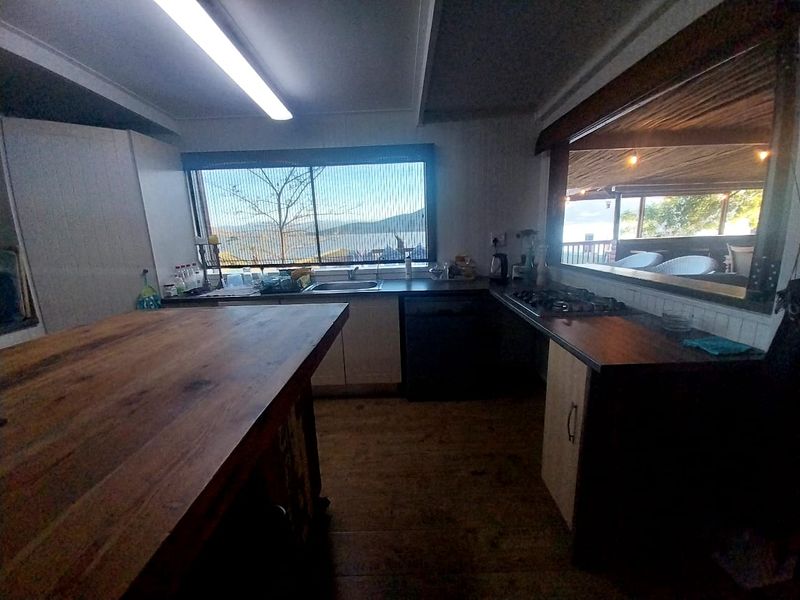 A functional kitchen featuring a large wooden island, built-in hob, and sink with a view, offering a practical layout for meal preparation.