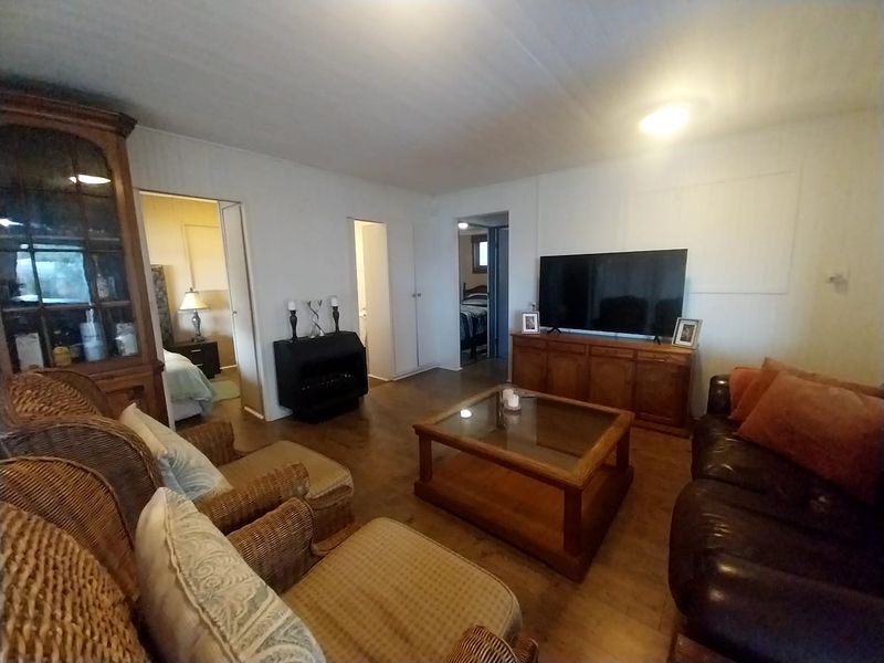 A living room featuring wood-look flooring and access to adjacent bedrooms, providing a functional and comfortable living space.
