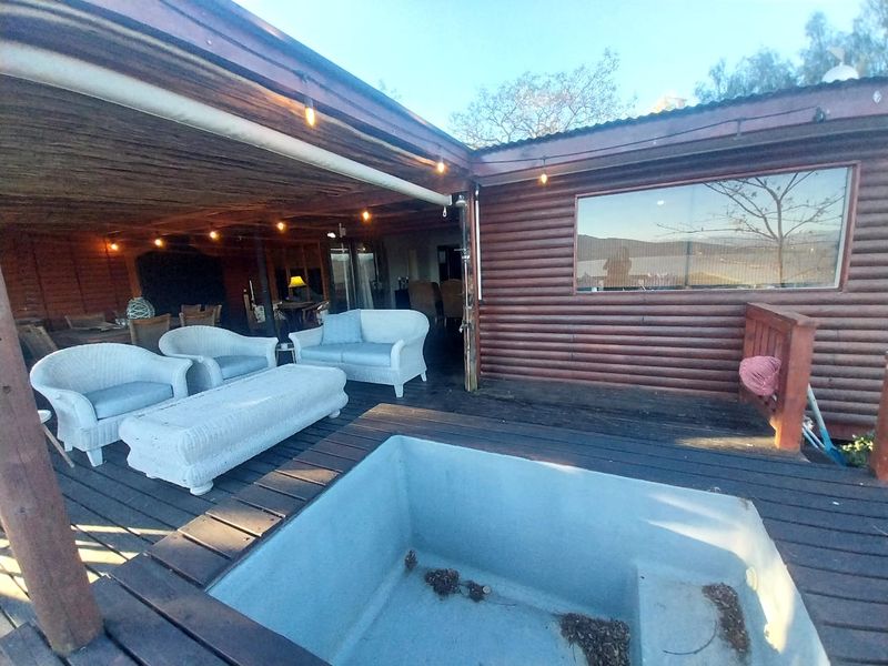 Covered outdoor patio area featuring timber decking, integrated pool, and log cabin style exterior walls, providing a rustic entertainment space.
