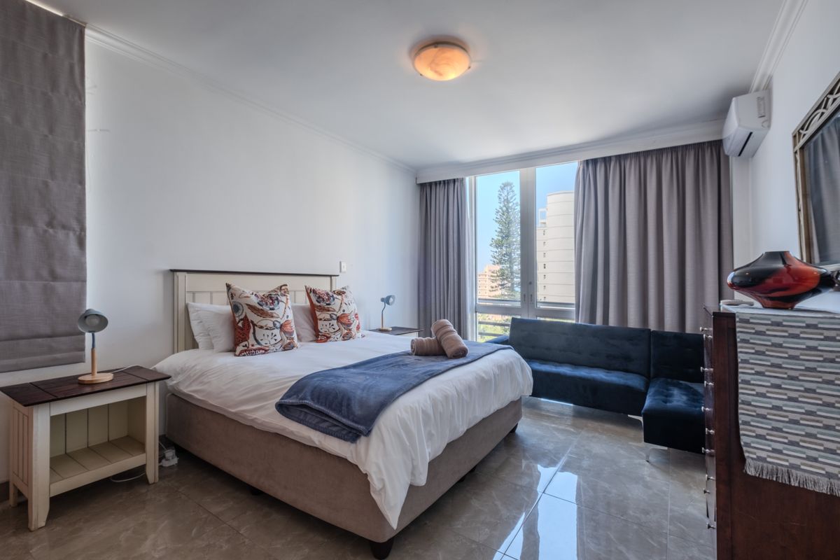A well-maintained bedroom featuring tiled flooring, a split-system air conditioner, and large windows providing natural light and exterior views.