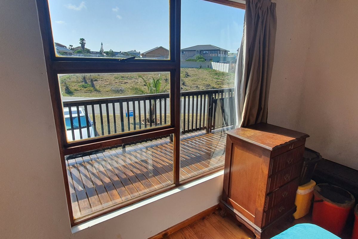 Bedroom featuring timber flooring and a large window with direct access to an outdoor timber deck and balustrade.
