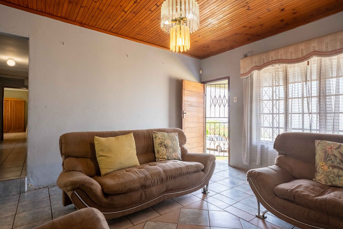 A living room featuring ceramic floor tiles, a timber tongue and groove ceiling, and direct access to the exterior via a security gate.