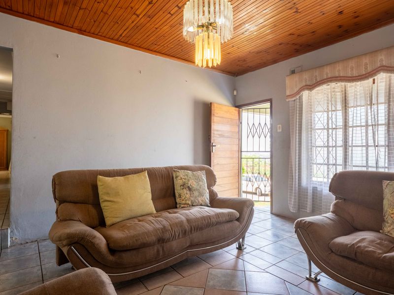 A living room featuring ceramic floor tiles, a timber tongue and groove ceiling, and direct access to the exterior via a security gate.