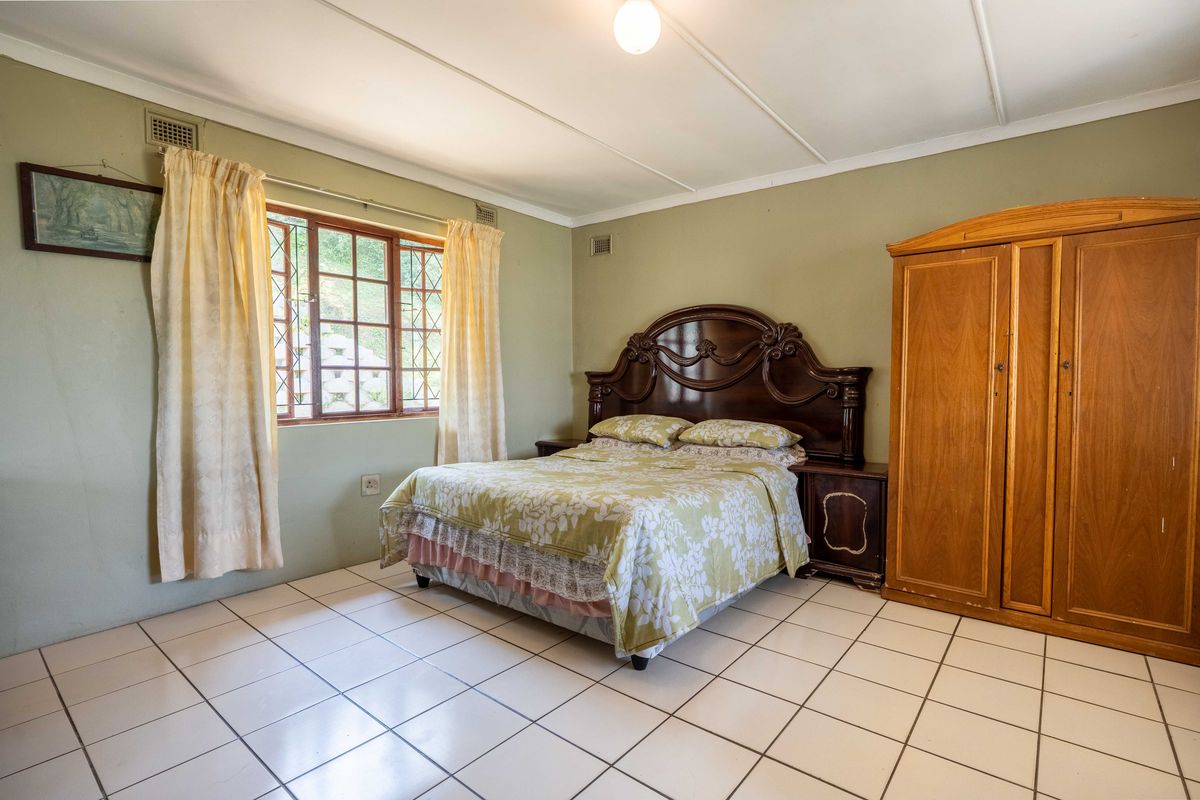 A bedroom featuring tiled flooring, a timber-framed window, and a ceiling vent. The space offers a functional layout ready for cosmetic updates.