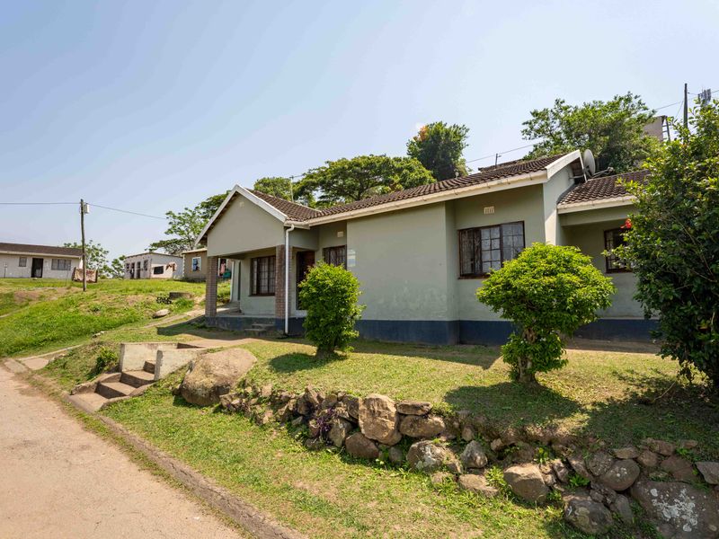 A single-story residential house featuring a tiled roof, steel window frames, and a stone retaining wall along the front garden area.