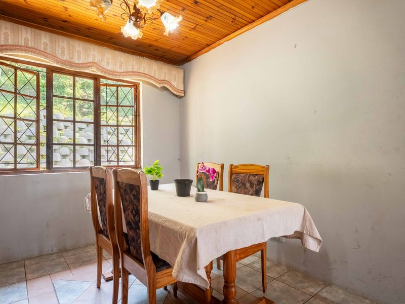 Dining room featuring a timber tongue and groove ceiling, ceramic tiled flooring, and a leaded glass window overlooking the exterior.