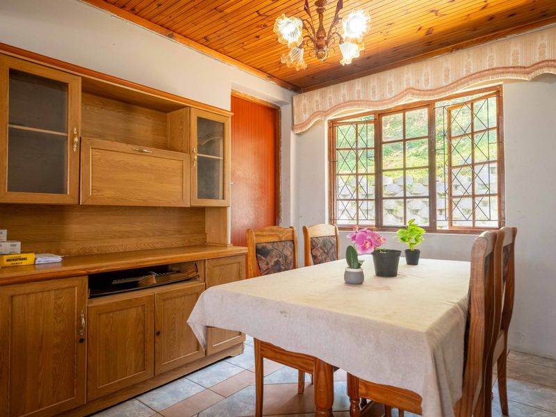 A dining room featuring a timber ceiling, tiled flooring, and built-in timber cabinetry, with natural light provided by leaded glass windows.