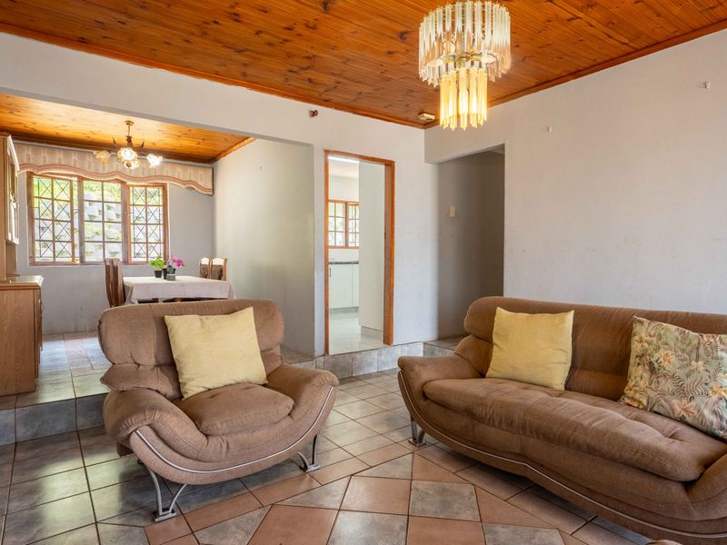 Open plan living and dining area featuring timber ceilings, ceramic tiled flooring, and classic leaded glass windows with access to the kitchen.
