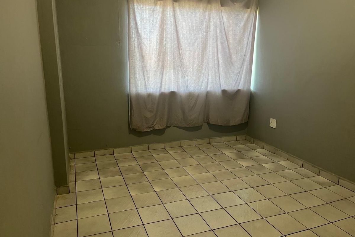 An empty bedroom featuring tiled flooring and neutral wall paint, providing a blank canvas for personalization.