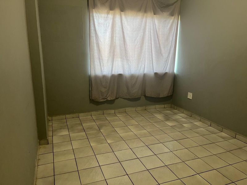 An empty bedroom featuring tiled flooring and neutral wall paint, providing a blank canvas for personalization.