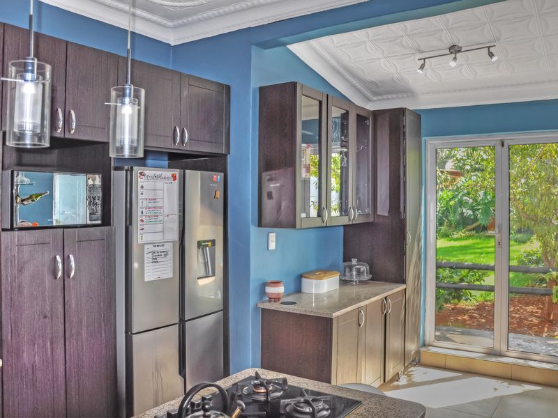 Modern kitchen featuring dark wood cabinetry, stone countertops, a gas cooktop, and direct access to the garden through a glass sliding door.
