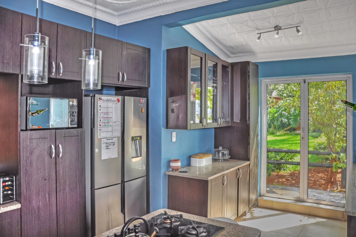 Modern kitchen featuring dark wood cabinetry, stone countertops, a gas cooktop, and direct access to the garden through a glass sliding door.