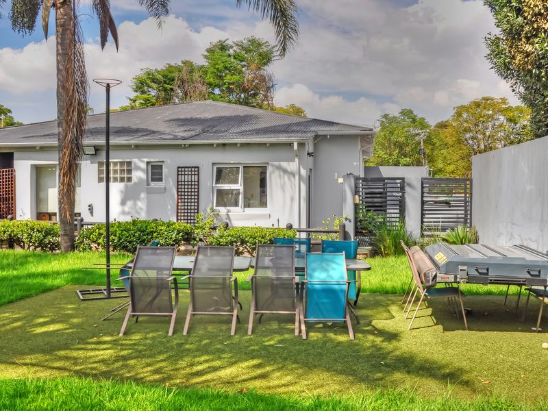 Rear view of the property featuring a low-maintenance artificial lawn, metal roof, and secure perimeter walling.