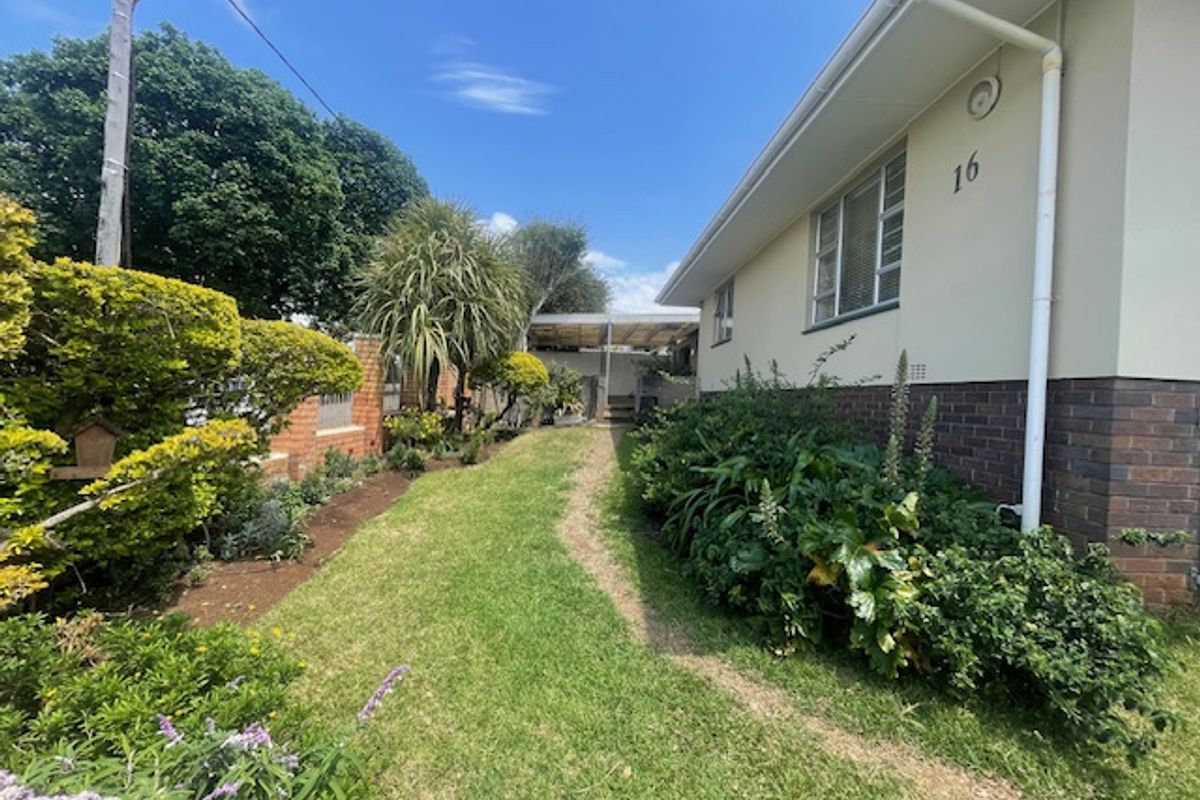 A well-maintained side garden area featuring a combination of brick and plastered exterior walls with established landscaping.