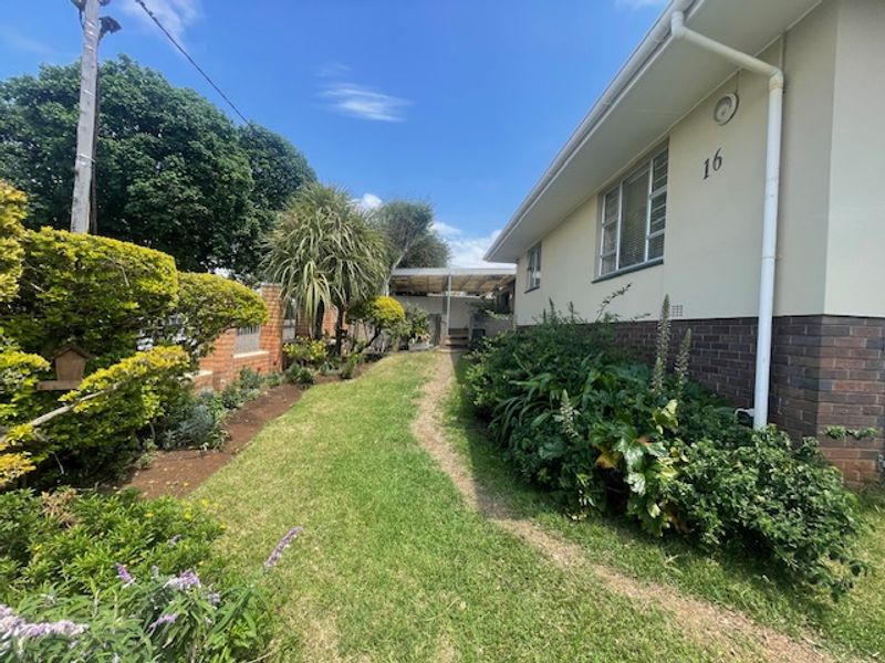 A well-maintained side garden area featuring a combination of brick and plastered exterior walls with established landscaping.
