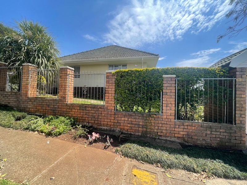 Front view of the property featuring a brick boundary wall with integrated metal fencing and a tiled roof structure.