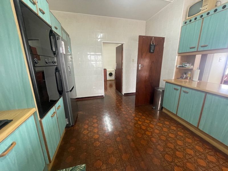 A functional kitchen featuring dated cabinetry, tiled wall finishes, and a built-in oven, with an adjacent utility area visible through the doorway.