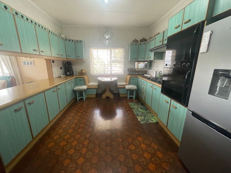 A spacious kitchen featuring extensive built-in cabinetry, a built-in oven, hob, and a cozy integrated breakfast nook area.