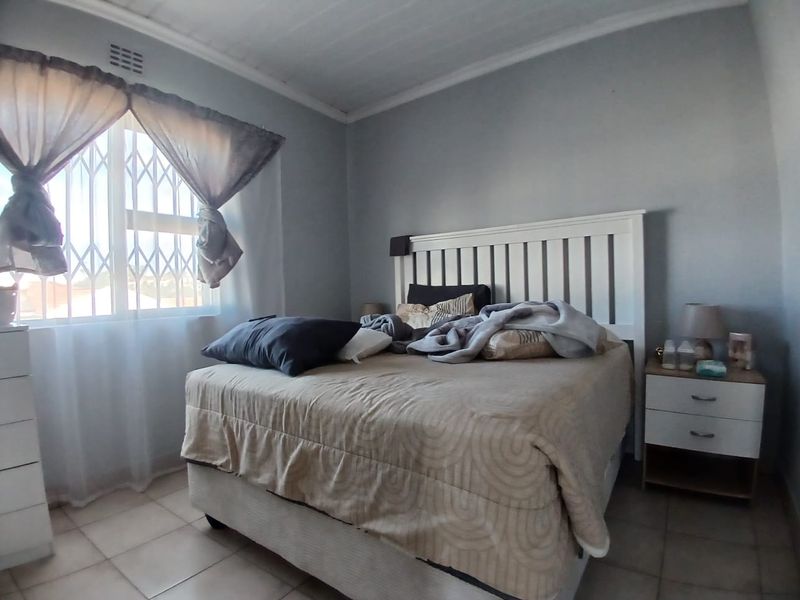 A bedroom featuring tiled flooring, a timber ceiling, and a window fitted with a security gate.