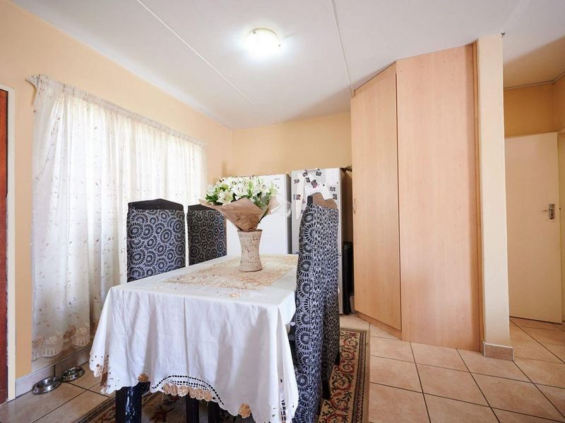 A dining area featuring tiled flooring and a built-in storage cupboard, providing a functional space for meals.