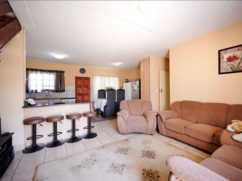 Open plan living and kitchen area featuring tiled flooring, a breakfast bar, and direct access to the upper level via a staircase.