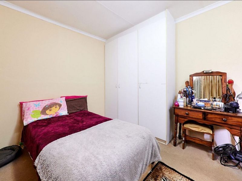 A standard bedroom featuring neutral wall finishes, carpeted flooring, and a white built-in wardrobe providing ample storage space.