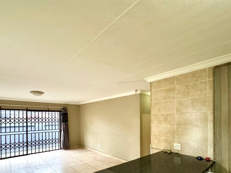 Open plan living area featuring tiled flooring, built-in cabinetry with granite countertops, and a security gate over the window.