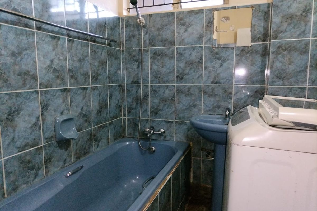 A dated bathroom featuring blue sanitaryware, tiled walls, and a pedestal basin, requiring modernization to improve its aesthetic appeal and functionality.