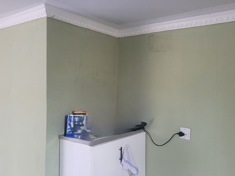 A corner view of a kitchen area featuring built-in cabinetry, decorative crown molding, and wall-mounted electrical points.