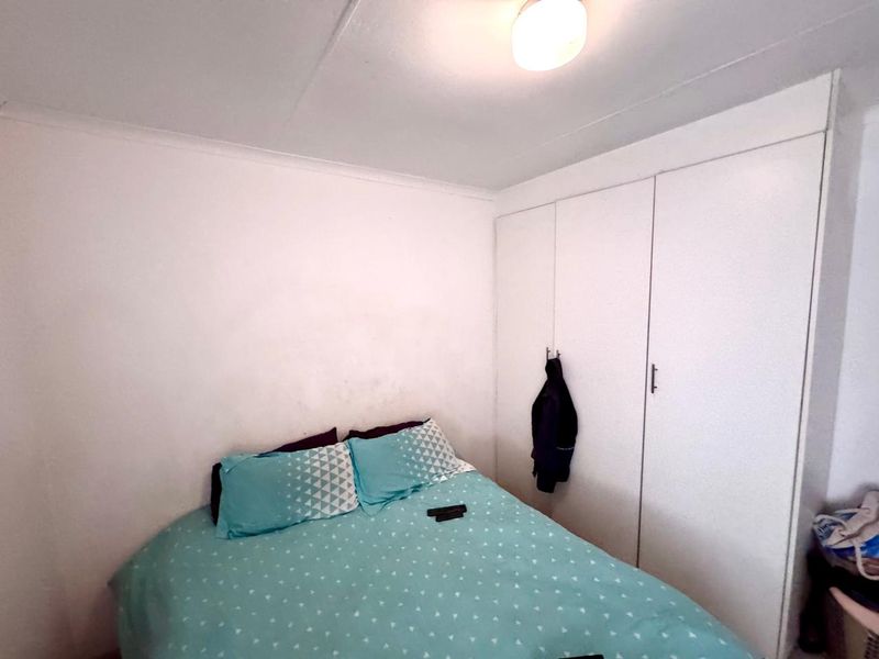 A functional bedroom featuring built-in cupboards and a central ceiling light fixture, providing essential storage and lighting.
