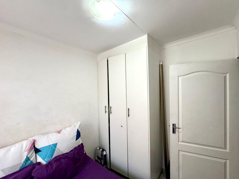 A bedroom featuring a white built-in wardrobe, coved ceiling, and a standard panel door, providing functional storage space.