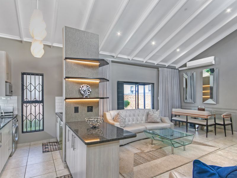 Modern open-plan living area featuring a vaulted ceiling with exposed beams, sleek kitchen cabinetry, granite countertops, and integrated lighting, creating a bright, cohesive space.