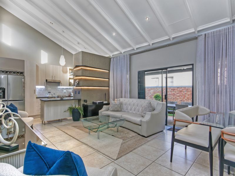Modern open-plan living area featuring a vaulted ceiling, tiled floors, and a contemporary kitchen with integrated cabinetry and stylish accent lighting.