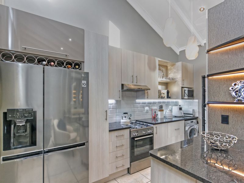 Modern kitchen featuring high-end cabinetry, granite countertops, subway tile backsplash, integrated appliances, and a striking vaulted ceiling with ambient lighting.