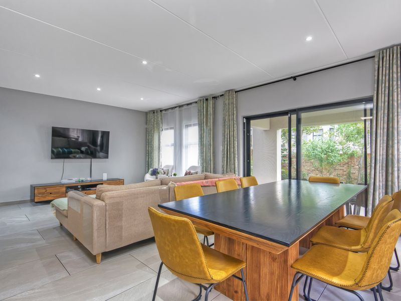 Spacious open-plan living and dining area featuring large format floor tiles, recessed lighting, and sliding glass doors providing access to the patio.