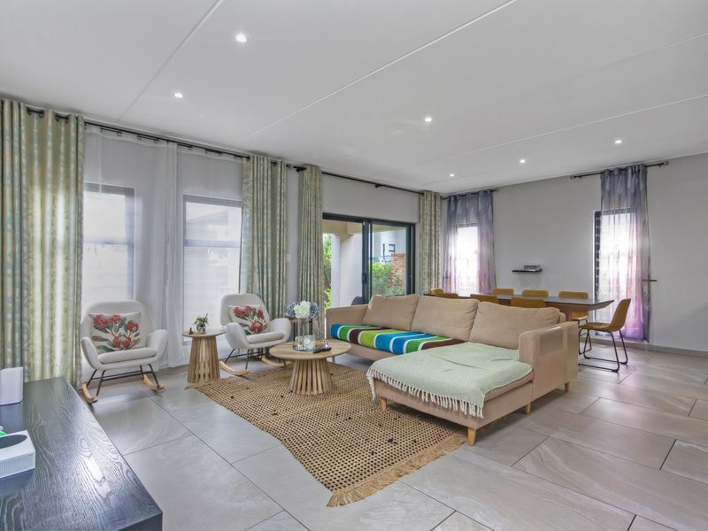 Spacious open-plan living and dining area featuring large windows, tiled flooring, and recessed lighting, providing a bright and airy atmosphere.